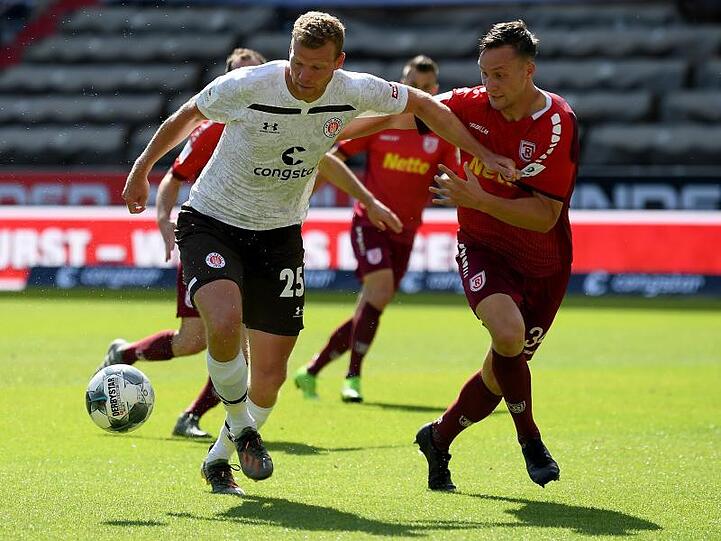 Henk Veerman (l) von Pauli und Tim Knipping von Regensburg kämpfen um den Ball. Foto: Stuart Franklin/Getty-Pool/dpa