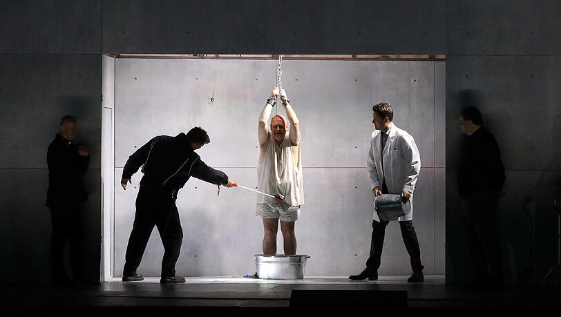 Christian Rieger, Wolfgang Koch und Jochen Kupfer in einer Folterszene in der Oper "Die Teufel von Loudun" im Nationaltheater. Koch musste sich in der Premiere krankheitsbedingt von Robert Dölle (Darstellung) und Jordan Shanahan (Gesang) vertreten lassen.