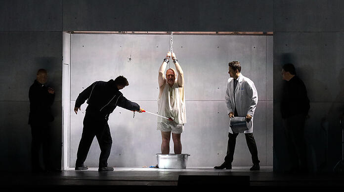 Christian Rieger, Wolfgang Koch und Jochen Kupfer in einer Folterszene in der Oper "Die Teufel von Loudun" im Nationaltheater. Koch musste sich in der Premiere krankheitsbedingt von Robert Dölle (Darstellung) und Jordan Shanahan (Gesang) vertreten lassen.