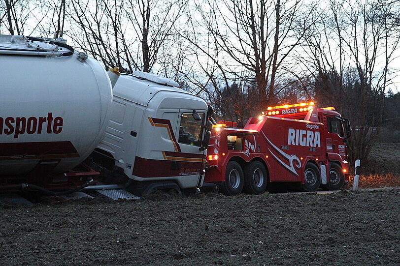 Ein Bergungsfahrzeug und zwei Kräne werden benötigt um den vollbeladenen LKW wieder auf die Straße zu ziehen.