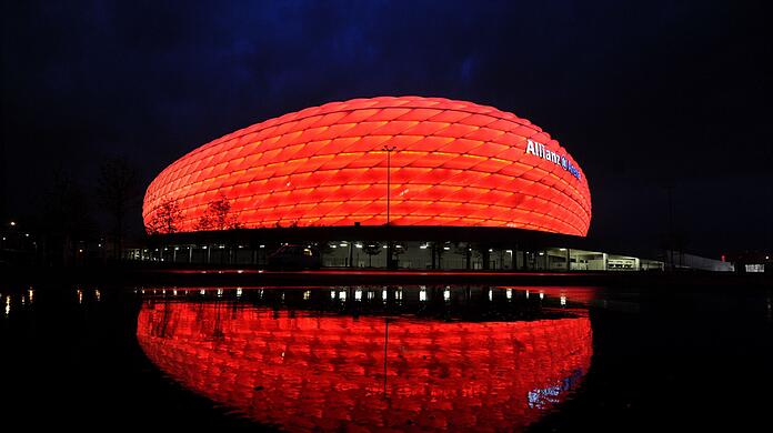 Wolken ziehen über die beleuchtete Allianz Arena.