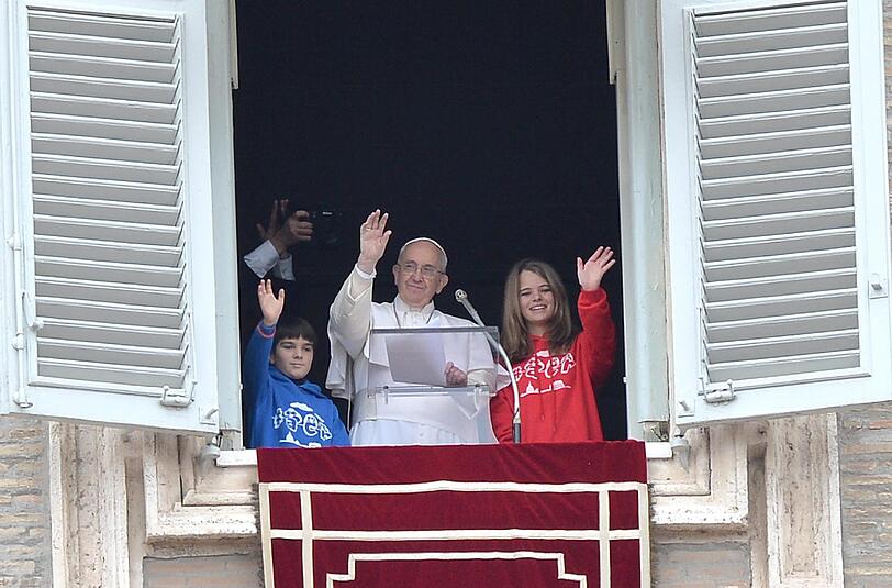 Der Papst winkt gemeinsam mit zwei Kindern den Pilgern und Touristen auf dem Petersplatz in Rom zu