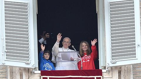 Der Papst winkt gemeinsam mit zwei Kindern den Pilgern und Touristen auf dem Petersplatz in Rom zu