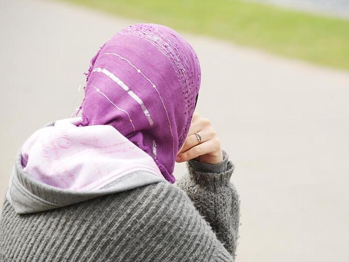 Eine junge Muslimin trägt ein Kopftuch zu einem modernen, westlichen Kapuzenpullover.