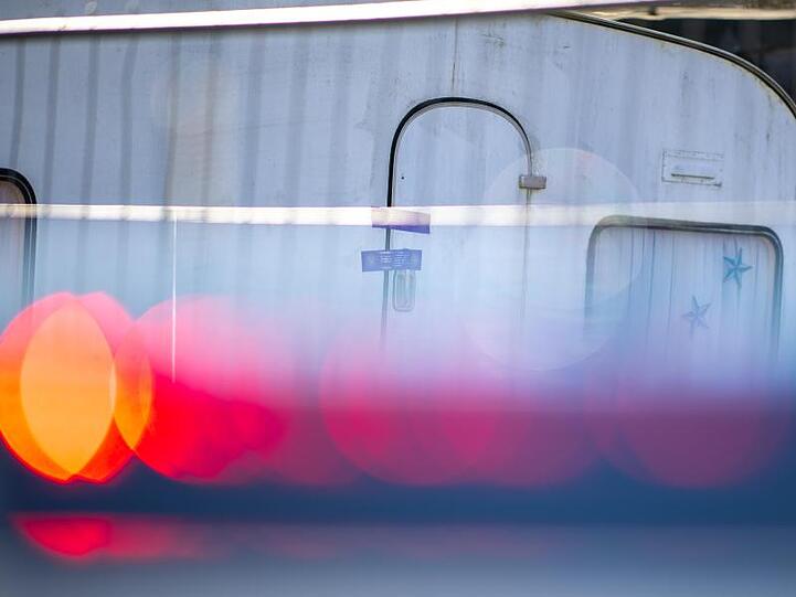 Ein Polizeiauto steht vor dem versiegelten Campingwagen des mutmaßlichen Täters.