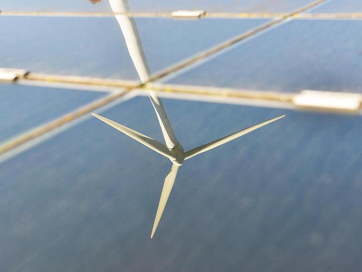 Ein Windrad spiegelt sich in den Kollektoren einer Solaranlage. Foto: Uli Deck