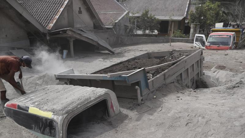 Ein Mann inspiziert einen Lastwagen, der nach dem Ausbruch des Mount Semeru unter Vulkanasche begraben wurde. Ein Mann inspiziert einen Lastwagen, der nach dem Ausbruch des Mount Semeru unter Vulkanasche begraben wurde.