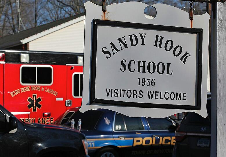 Rettungs- und Polizeiautos stehen vor der Sandy-Hook-Grundschule in Newton. Ein Amokläufer hat ein Blutbad abgerichtet und Dutzende Menschen erschossen, datunter mindestens 18 Kinder.