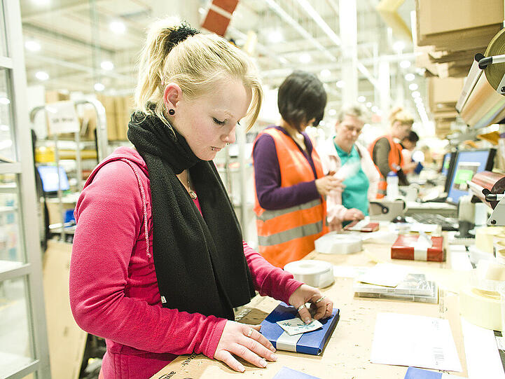 Eine Amazon-Mitarbeiterin im Logistikzentrum verpackt ein Geschenk