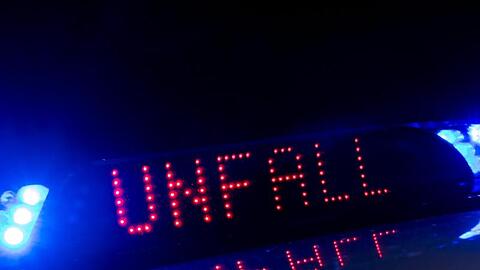 Zwischen den Blaulichtern auf einem Polizeifahrzeug warnt eine Leuchtschrift vor einem Unfall.