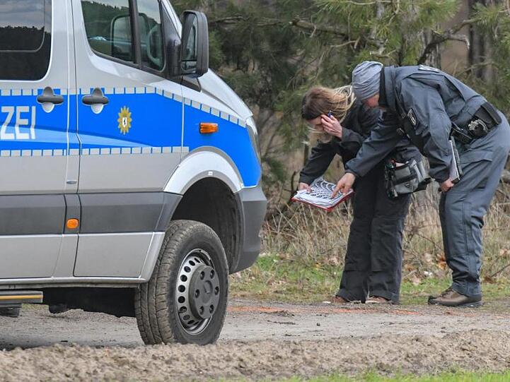 Kriminalbeamte halten nach Spuren wie Reifenabdrücken Ausschau.