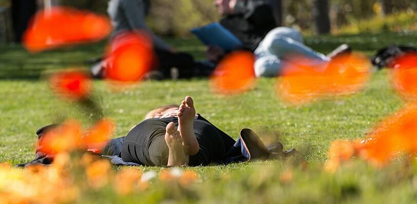 Auch in Freiburg lockt das Wetter zum entspannen in der Sonne wie diese Frau zeigt. Mit nackten Füßen liegt sie in der Innenstadt von Freiburg auf einer Rasenfläche.