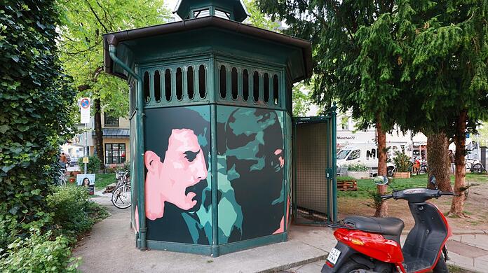 Graffiti-Kunst im Glockenbachviertel: Am Holzplatz ist das Porträt von Queen-Sänger Freddie Mercury zu sehen, denn er lebte viele Jahre im Viertel. Auf eine Platte gesprayt ist es auf diesem historischen Pavillon befestigt, das einmal ein Pissoir gewesen ist.