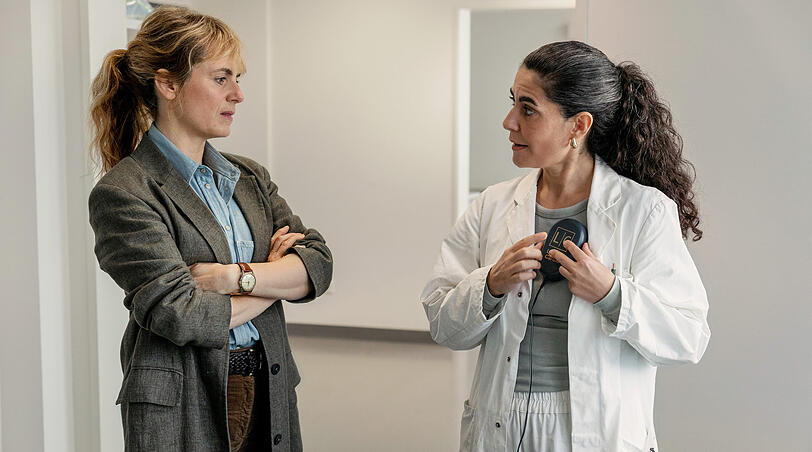 Dr. Şahin erklärt, wie das Update eines ICD-Geräts funktioniert: Kommissarin Isabelle Grandjean (Anna Pieri Zuercher) und Dr. Esme Şahin (Beren Tuna).