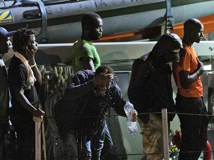 Migranten gehen von Bord eines italienischen Polizeiboots der Guardia di Finanza.