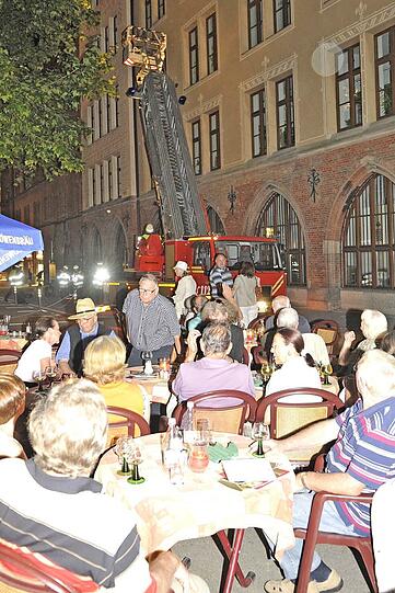 Woher kommt der Qualm? Mit einer Leiter suchen die Retter die Fassade ab. Gäste vom Ratskeller beobachten das Spektakel.