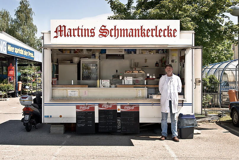 "Hier spricht der Preis", behauptet recht forsch der Praktiker- Baumarkt im Münchner Norden (links im Bild), vor dem sich 2008 "Martins Schmankerlecke" postiert hat. Martins Preise sprechen zwar nicht, können sich aber sehen lassen: Fleischpflanzl mit Kartoffelsalat für 2,50 Euro!
