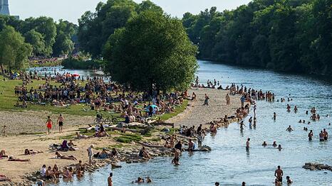 Menschen genießen das gute Wetter am Isarufer. Nicht nur Abkühlen im Wasser hilft gegen die Hitze.
