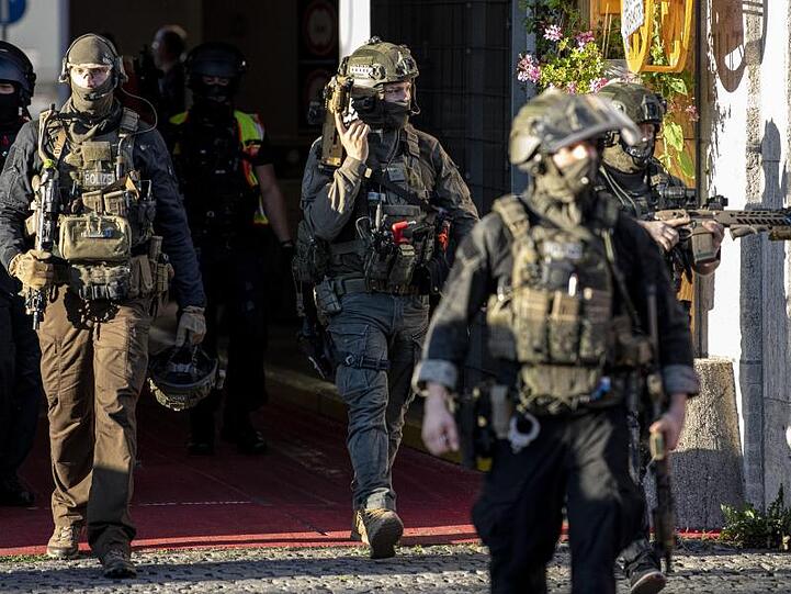 Schwer bewaffnete Polizeibeamte verlassen das Kaufhaus am Hermannplatz.