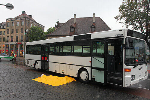 Die Retter haben die Leiche der 55-Jährigen abgedeckt. Sie war unter dem Bus eingeklemmt.