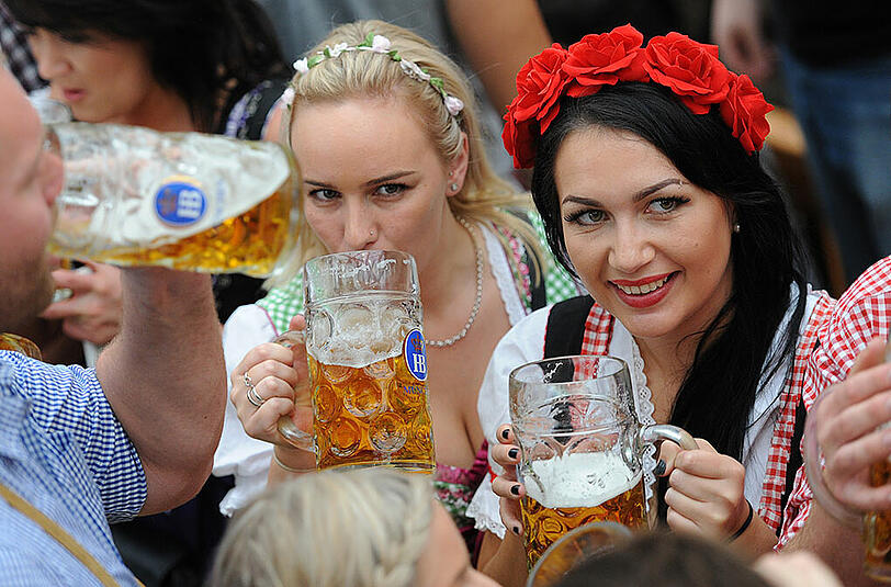 Wiesn-Besucherinnen lassen sich die erste Maß auf dem Oktoberfest schmecken.
