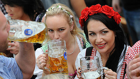Wiesn-Besucherinnen lassen sich die erste Maß auf dem Oktoberfest schmecken.