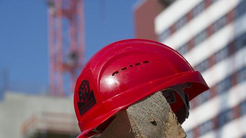 Ein Bauhelm liegt auf einem Holzbalken.