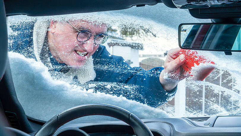 Ein Autofahrer macht seinen Wagen im Winter bereit, um sicher in den Verkehr zu starten. Ein Autofahrer macht seinen Wagen im Winter bereit, um sicher in den Verkehr zu starten.