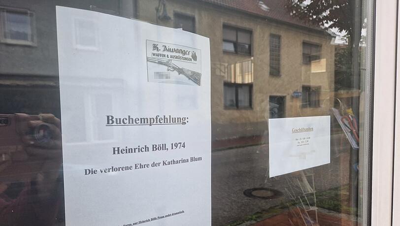 An der Tür des Waffenladens von Helmut Aiwanger hängt eine Buchempfehlung: "Die verlorene Ehre der Katharina Blum" von Heinrich Böll. An der Tür des Waffenladens von Helmut Aiwanger hängt eine Buchempfehlung: "Die verlorene Ehre der Katharina Blum" von Heinrich Böll.