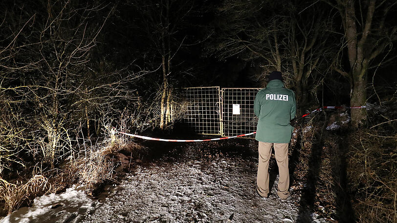 Ein Polizist steht vor der Einfahrt zur Gartenlaube, in der die sechs Toten gefunden wurden.