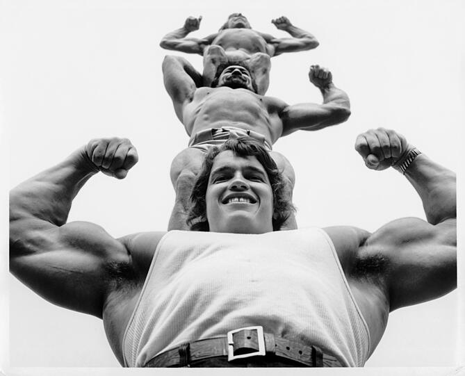 Herkules Schwarzenegger tr&auml;gt zwei Artisten auf seinen riesigen Schultern (1970).