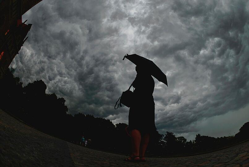 Eine Frau mit Regenschirm steht am 20.06.2013 vor dem Neuen Rathaus in Hannover.