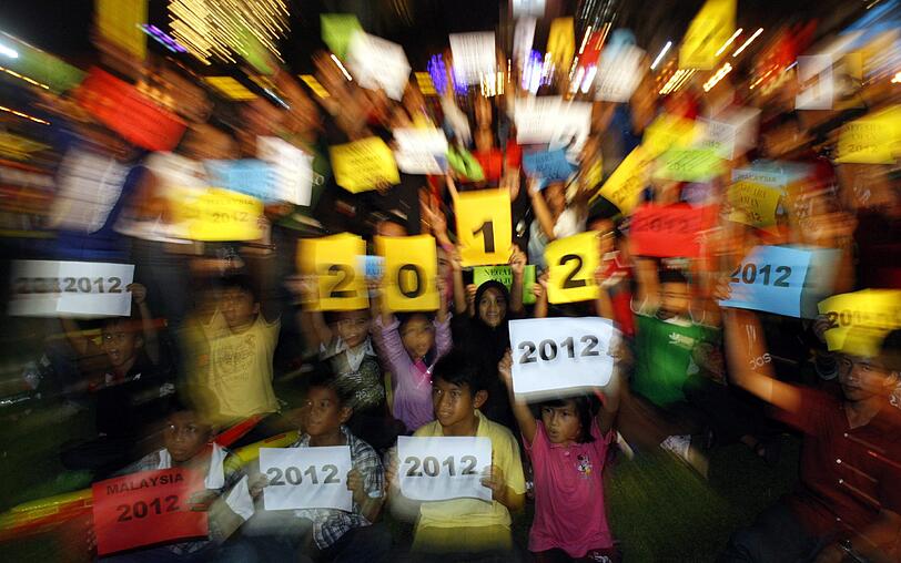 Auf dem Unabhängigkeitsplatz in Kuala Lumpur halten Malaysier Karten mit der Aufschrift "2012" in die Höhe.