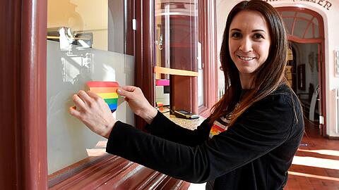 Eine Mitarbeiterin des Müller'schen Volksbads bringt einen Regenbogen-Aufkleber an.