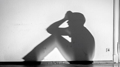 Die Schatten eines hilfsbedürftigen, psychisch kranken Menschen an einer Wand (Symbolbild).
