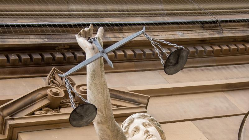 Eine Statue der Justitia hält eine Waagschale in der Hand.