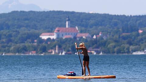 Eine Stand-Up-Paddlerin vor mit dem Marienmünster in Dießen am Ammersee (Archivbild)