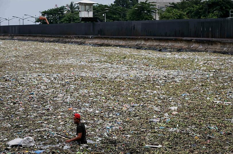 Treibmüll: In Manila watet ein Mann durch ein vermülltes Hafenbecken. Die philippinische Hauptstadt hat noch immer mit den Folgen von Taifun Nida zu kämpfen. Foto: Mark R. Cristino