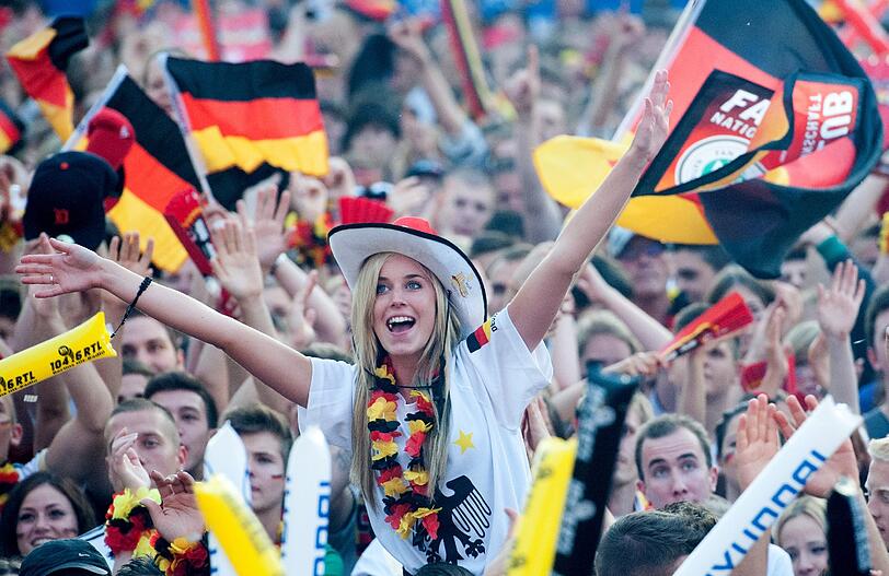 Fahnen, Masken, gute Laune: Hier feiern die Fans mit ihrer deutschen Elf den 4:2-Sieg gegen Griechenland. Am Münchner Flughafen kann zum Halfinale nicht mehr mitgejubelt werden: Die Übertragungen dort wurden gestrichen - wegen zu großen Ansturms.