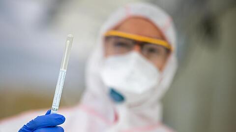 Ein Mitarbeiter hält in einem Abstrichzentrum einen Coronatest-Abstrich in der Hand. Foto: Sebastian Gollnow/dpa/Symbolbild