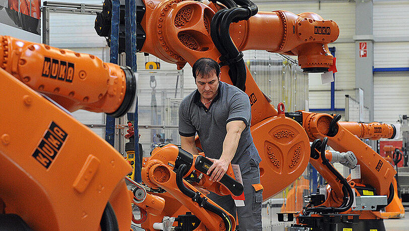 Ein Arbeiter kontrolliert in Augsburg (Bayern) einen Roboter von Kuka. Ein Arbeiter kontrolliert in Augsburg (Bayern) einen Roboter von Kuka.