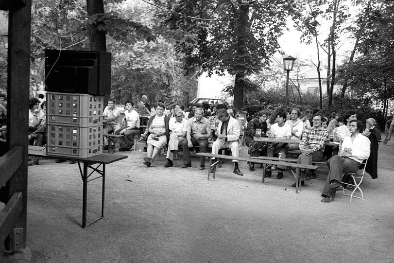 Der Fernseher ist drapiert, die Biergartengäste haben sich brav hingruppiert - das erste Public Viewing Deutschlands!