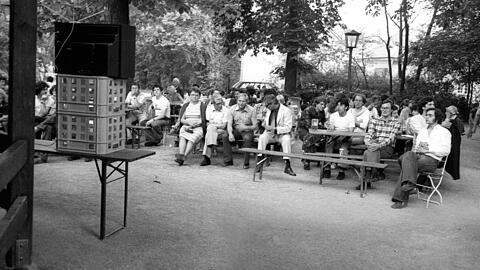 Der Fernseher ist drapiert, die Biergartengäste haben sich brav hingruppiert - das erste Public Viewing Deutschlands!