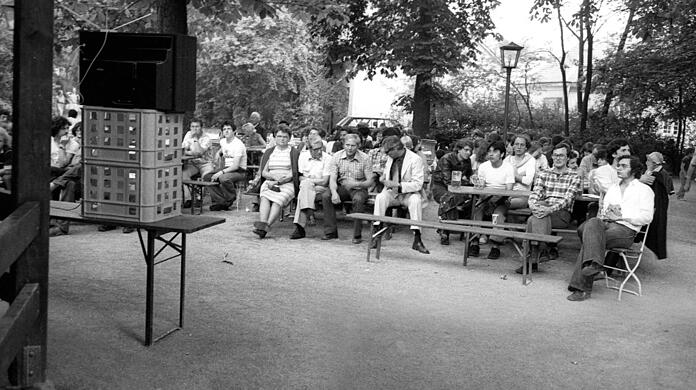 Der Fernseher ist drapiert, die Biergartengäste haben sich brav hingruppiert - das erste Public Viewing Deutschlands!