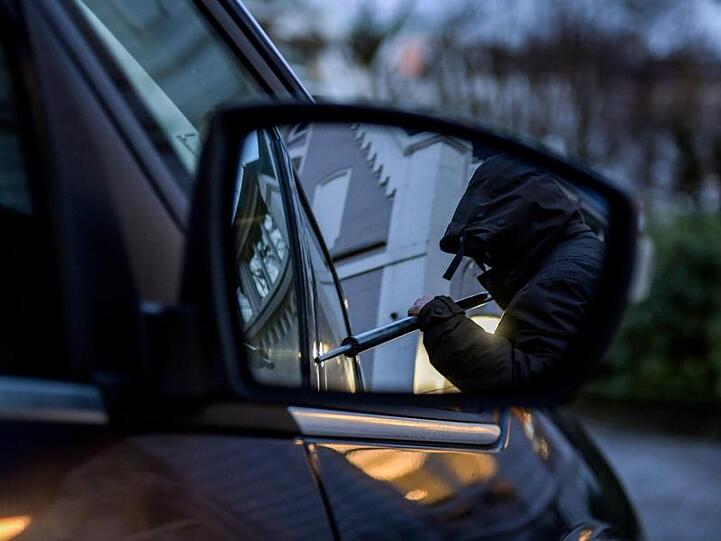 Ein Mann versucht eine Autotür mit einer Metallstange aufzubrechen (gestellte Szene). Foto: Axel Heimken/dpa/Symbolbild