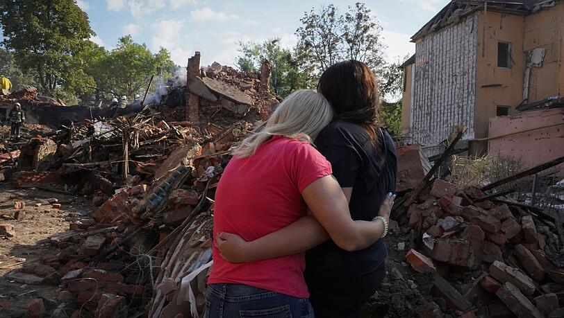 Ukrainische Frauen stehen vor den Trümmern eines Hauses in Charkiw, das bei einem Raketenangriff zerstört wurde.