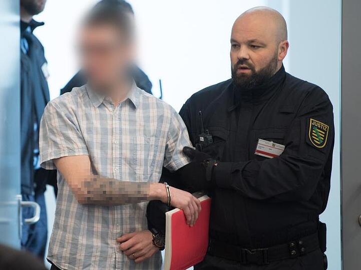 Ein Angeklagter wird im Oberlandesgericht Dresden zu Prozessbeginn in den Verhandlungssaal geführt.