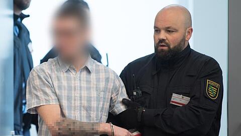 Ein Angeklagter wird im Oberlandesgericht Dresden zu Prozessbeginn in den Verhandlungssaal geführt.