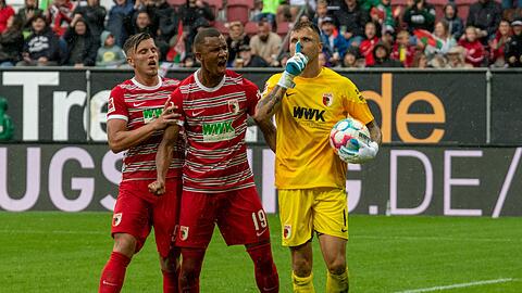 Augsburgs Torwart Rafal Gikiewicz (r) lässt sich von Emirdan Demirovic (l) und Felix Uduokhai feiern.