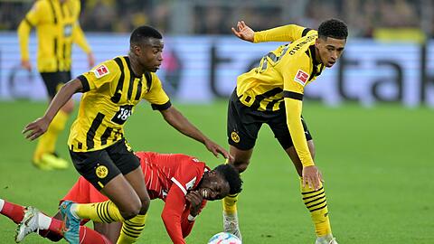 Alphonso Davies (M) kämpft gegen Jude Bellingham (r) und Youssoufa Moukoko um den Ball.